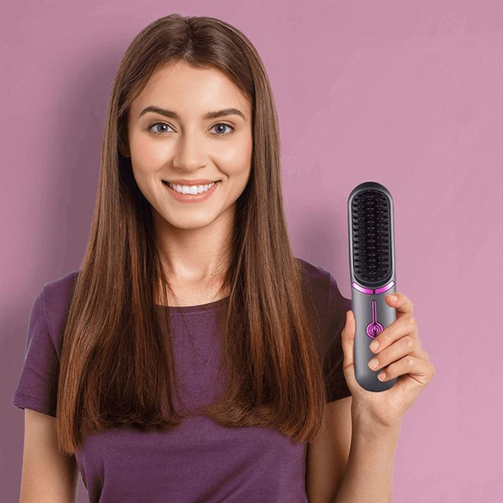 A smiling woman with straight brown hair stands against a lavender background, holding the UNIQ 2-in-1 Straightening Brush with Ceramic Plates—featuring fast heating and USB-C charging—in her right hand, ready to style her hair.