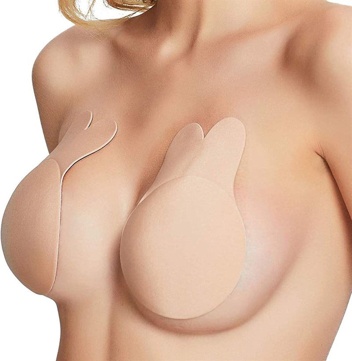 A woman uses Shapelux Lifting Pads for Invisible Breast Lift, a beige strapless bra alternative with strong adhesive tape that offers support and coverage without visible straps.