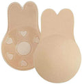 Shapelux Lifting Pads voor onzichtbare borstlift zijn beige, herbruikbare siliconen hoesjes met konijnenoren en sterke plakband. De ene laat de gladde voorkant zien, de andere heeft hartvormige uitsparingen en gestructureerde plakband voor een strapless bh-alternatief.