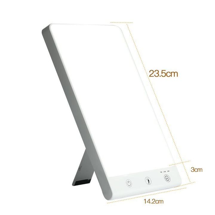 The Fashiongirl Light Therapy Lamp 10,000 lux LED is a rectangular white lamp with touch controls and a built-in stand. Its artificial daylight helps ease winter depression. Dimensions: 23.5 cm tall, 14.2 cm wide, 3 cm thick.