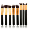 De PRO Makeup Brush Set Black/Gold van PRO bevat 10 premium kabuki- en precisieborstels met zwarte handvatten, gouden ferrules en zachte haren, allemaal rechtop op een rij tegen een witte achtergrond voor een vlekkeloze applicatie.