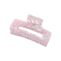 De SOHO Clara Hair Claw - Lavender Pink is een grote rechthoekige acrylclip in roze en wit marmer met een glanzende, doorschijnende afwerking en een veerscharnier - ideaal als XL-haaraccessoire voor dik haar.