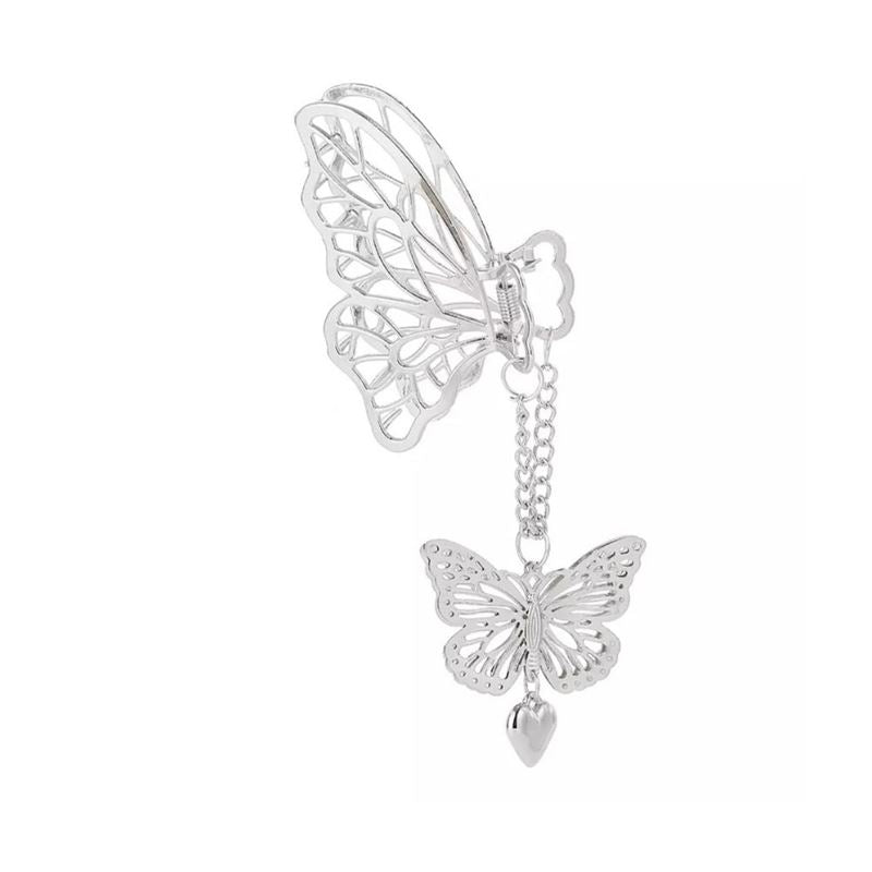 A silver butterfly ear cuff with a dangling chain, butterfly charm, and heart pendant—perfect to pair with your SOHO Emy Metal Hair Claw - Butterfly from SOHO.