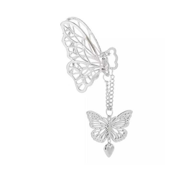 A silver butterfly ear cuff with a dangling chain, butterfly charm, and heart pendant—perfect to pair with your SOHO Emy Metal Hair Claw - Butterfly from SOHO.