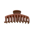 De SOHO Kana Hair Claw in Bark Brown, van SOHO, is een plastic haarclip met gebogen, in elkaar grijpende tanden voor een stevige grip. Afgebeeld vanaf de voorkant op een witte achtergrond, geschikt voor alle haartypes.