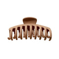 De SOHO Kana Hair Claw - Beige heeft brede, gebogen tanden voor een sterke grip op alle haartypes en wordt afgebeeld tegen een witte achtergrond.