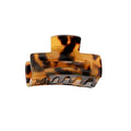 De SOHO Leia Mini Hair Claw - Tortoise van SOHO heeft een bruin schildpadpatroon, een gebogen ontwerp en in elkaar grijpende tanden voor een stevige grip. Perfect als kleine haarclip voor eenvoudige styling en om het haar op zijn plaats te houden.