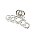 Zeven glanzende metalen ringen van verschillende grootte, geïnspireerd op de elegante rondingen van de SOHO Metal Hair Claw - Silver van SOHO, zijn in een lijn gerangschikt als een rups op een witte achtergrond.