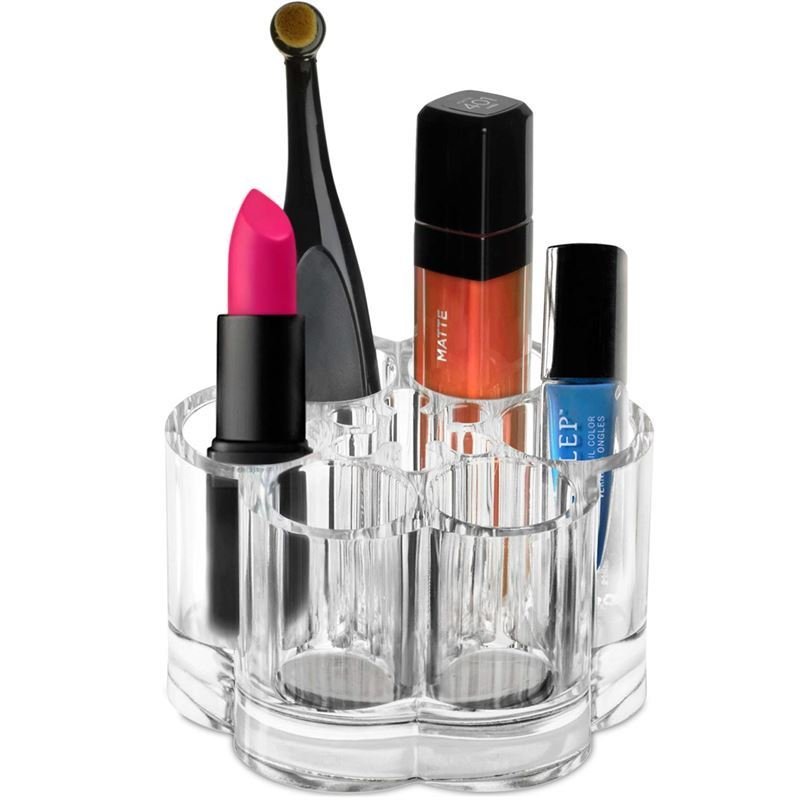 The UNIQ Flower Makeup Acrylic Organiser - U301 by UNIQ features multiple compartments to hold items like pink lipstick, an applicator brush, orange lip gloss, nail polish, and a blue nail polish bottle. This stylish organiser stands out on a white background.