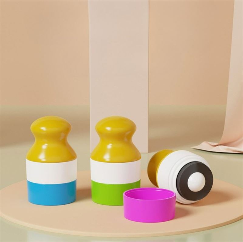 Three colorful UNIQ Portable Refillable Sponge Roller Applicators (100ml) by UNIQ are shown, with rounded yellow tops and white bodies—one revealing its black-and-white base. A pink cap rests nearby on a beige surface; ideal for mess-free sunscreen & lotion for kids.
