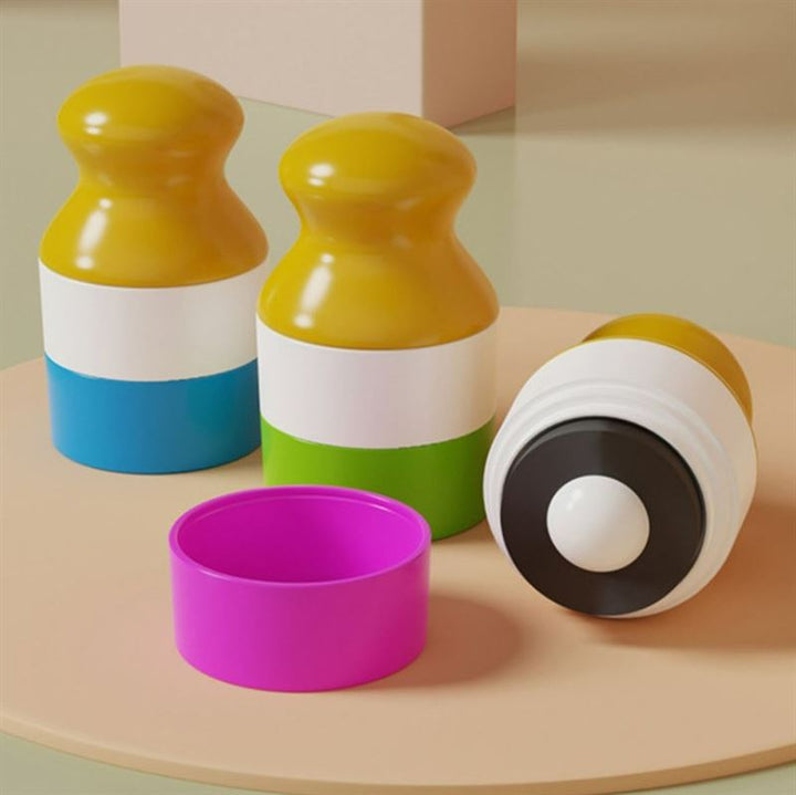 Three colorful UNIQ Portable Refillable Sponge Roller Applicators (100ml) for mess-free sunscreen and lotion application for kids rest on a beige surface, with one cap off to show the black and white sponge tip. Their sleek design stands out in the minimalistic setting.