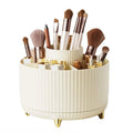 De UNIQ Rotating Makeup Organiser in Cream White heeft een gelaagd, geribbeld ontwerp met vakken en gouden pootjes, waardoor je kwasten, lippenstiften, potloden en beautyproducten gemakkelijk kunt opbergen en ordenen.